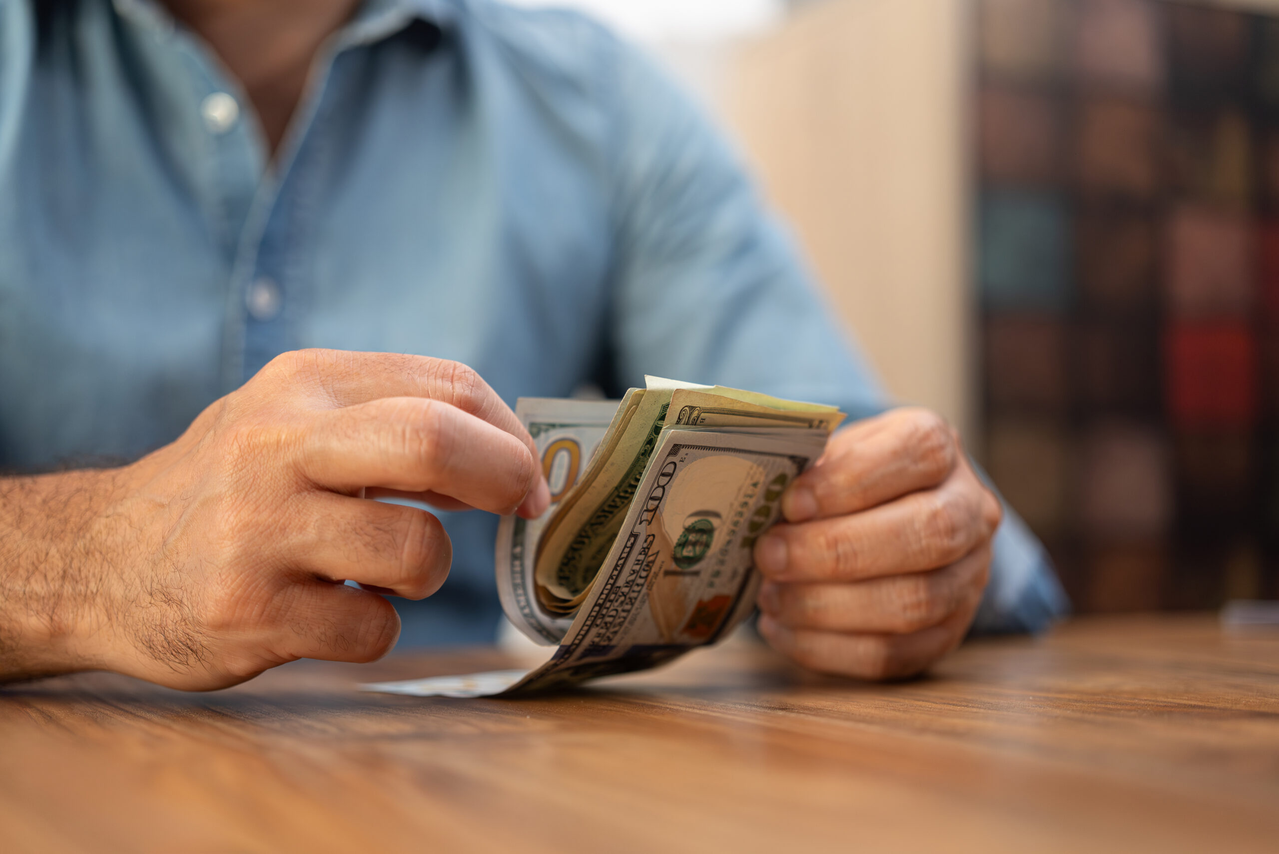 Male entrepreneur holds pack of dollar banknotes in hands carefully counting money for investment